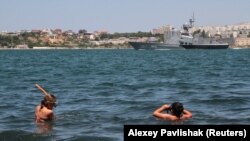 Крим, Севастополь, 2019 рік, відпочивальники на фоні російського військового корабля
