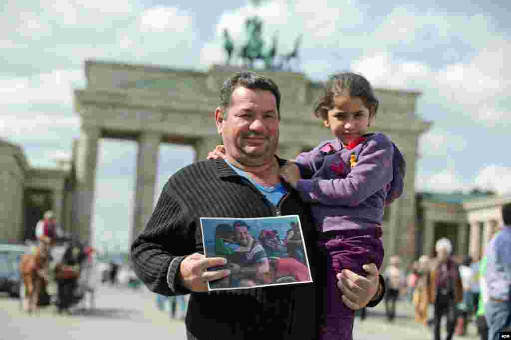 Syrian refugee Laith Majid Al-Amirij and his 7-year-old daughter Noor pose in front of the Brandenburg Gate in Berlin while holding a famous photo showing them during their crossing to the Greek island of Kos The photo was seen around the world and shared thousands of times on social media. The family are now being housed in Berlin. (epa/Joerg Carstensen)