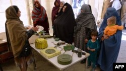 An Afghan aid worker (L) shows examples of bombs and mines to returning Afghan refugee families at a United Nations High Commissioner for Refugees (UNHCR) center on the outskirts of Jalalabad (file photo).