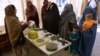 An Afghan aid worker (L) shows examples of bombs and mines to returning Afghan refugee families at a United Nations High Commissioner for Refugees (UNHCR) center on the outskirts of Jalalabad (file photo).