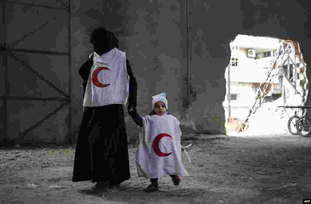 A Syrian woman and a child wait before being evacuated by members of the Syrian Red Crescent from a rebel-controlled area of Aleppo. (AFP/Karam al-Masri)