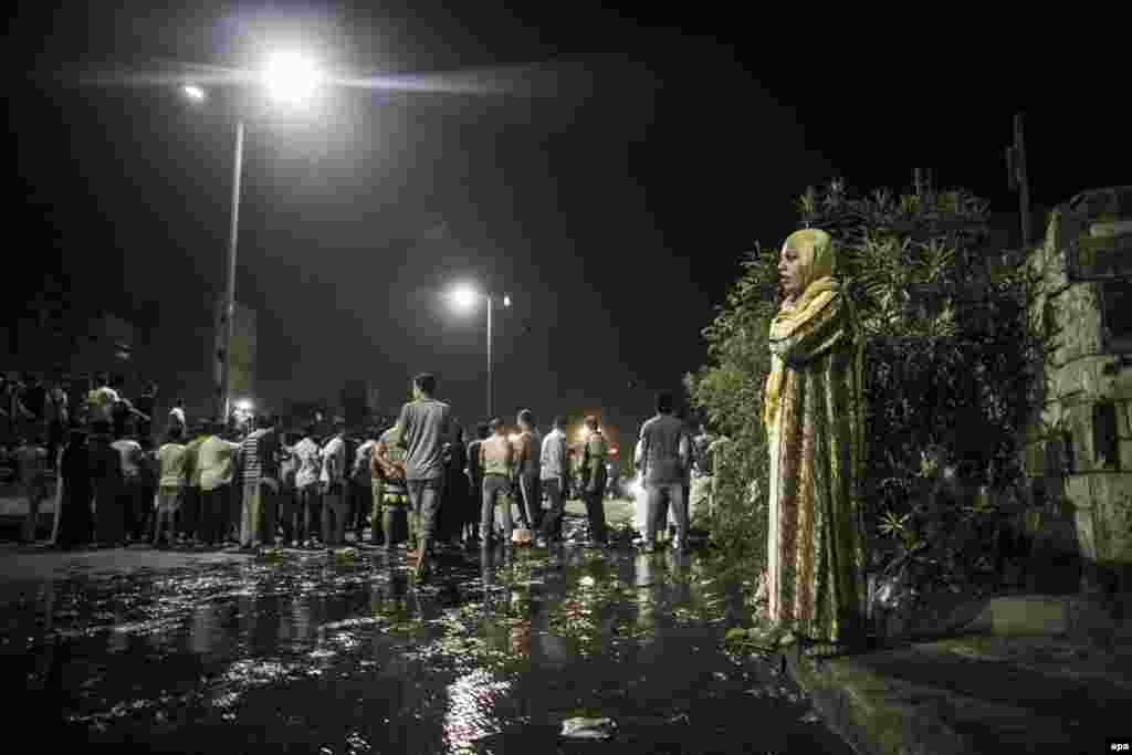 Local residents stand near the scene where a bomb detonated next to a national security building in the Shubra neighborhood of Cairo, Egypt, on August 20. (epa/Oliver Weiken)