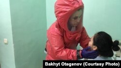 Медик в защитном костюме проводит осмотр пациента. Иллюстративное фото.