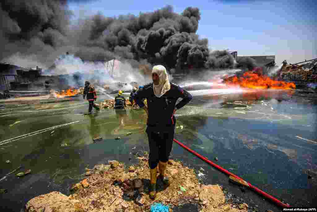 An Iraqi firefighter looks on as colleagues attempt to extinguish a blaze that broke out due to extreme summer temperatures in Baghdad on July 10. (AFP/Ahmad Al-Rubaye)