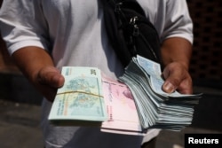 A currency dealer holds Iranian rials in the Grand Bazaar in Tehran on August 17.