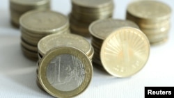 Macedonia -- An one euro coin is balanced against stacks of Macedonian one denar coins, 25Jan2011