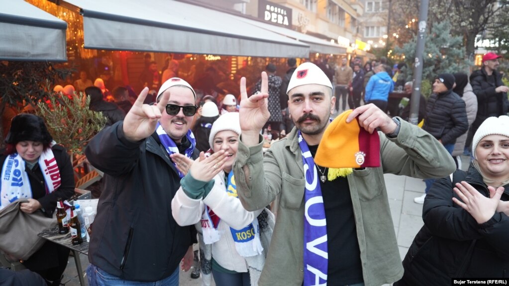 Disa tifozë me plisa tradicional shqiptar dhe shall më emrin Kosova mbi supe, teksa dy gra bëjnë simbolin e shqiponjës dykrenore, e cila gjendet në flamurin kombëtar shqiptar.