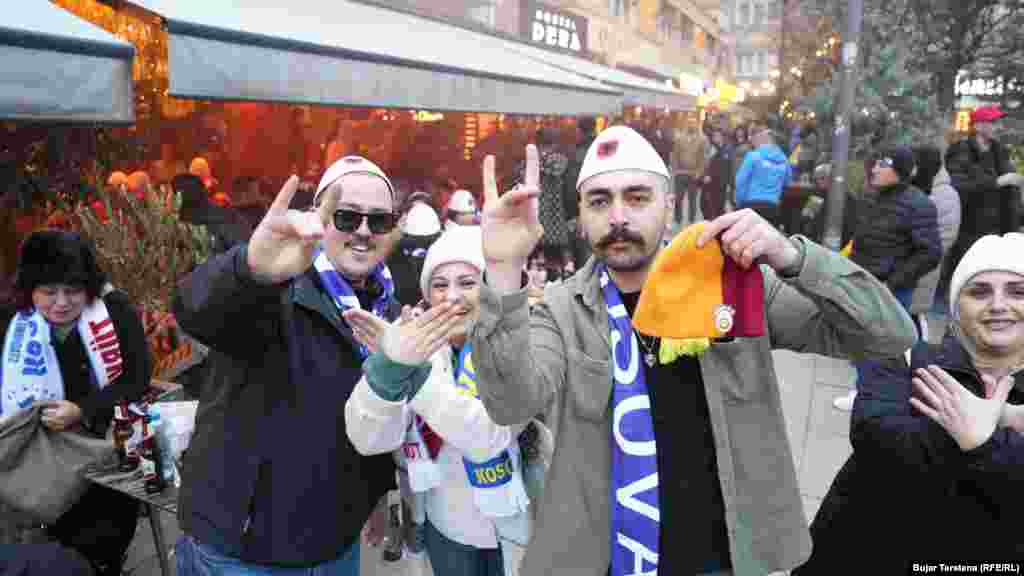 Disa tifozë me plisa tradicional shqiptar dhe shall më emrin Kosova mbi supe, teksa dy gra bëjnë simbolin e shqiponjës dykrenore, e cila gjendet në flamurin kombëtar shqiptar.