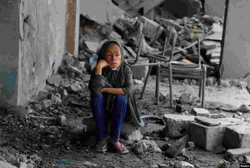 O fetiță palestiniană este surprinsă printre dărâmăturile unei școli a Națiunilor Unite unde se adăposteau persoane strămutate, după ce clădirea a fost bombardată. Imagine din cartierul Zeitoun din orașul Gaza, 1 octombrie 2025.În timp ce pagubele războiului care a durat doi ani sunt estimate la zeci de miliarde de dolari, consecințele viitoare ale războiului sunt greu de cuantificat.