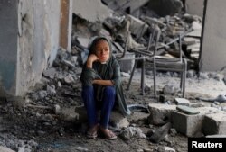 O tânără palestiniană stă în mijlocul dărâmăturilor unei școli a Națiunilor Unite unde se adăposteau persoane strămutate, după ce aceasta a fost lovită în timpul unei operațiuni militare israeliene. Cartierul Zeitoun din orașul Gaza, 1 octombrie 2025.