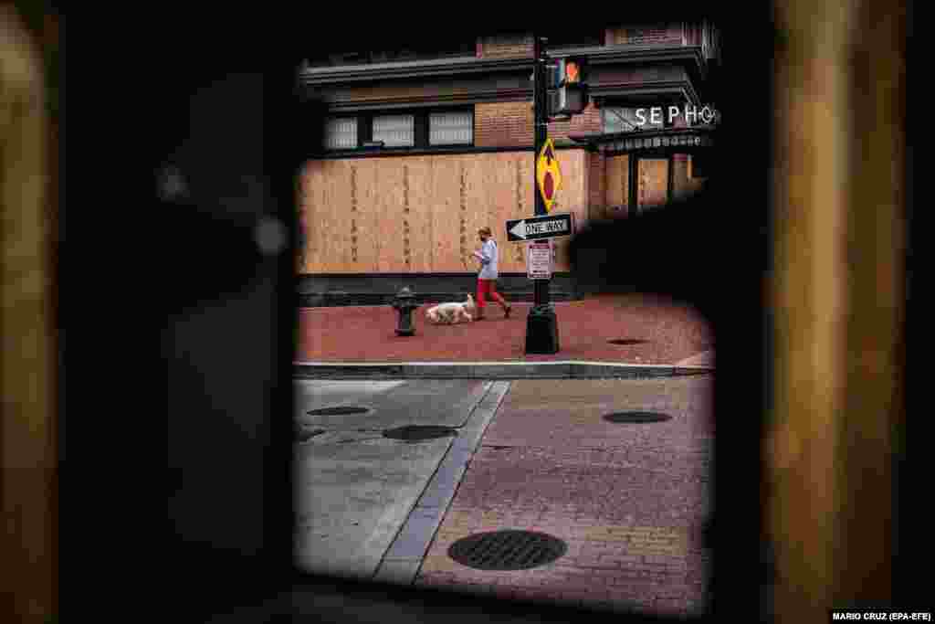 Дівчина проходить повз крамницю, захищену дерев&#39;яними дошками. Вашингтон, округ Колумбія, США