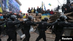 A line of riot police marches past pro-European integration protesters manning barricades on Independence Square in Kyiv on December 11. 