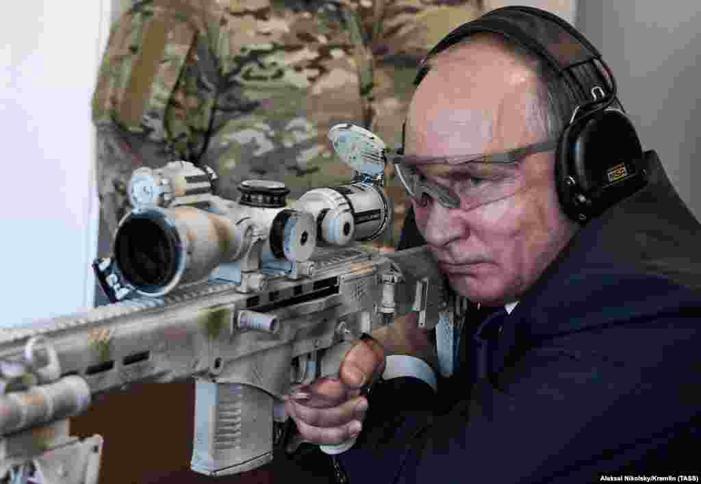 Russian President Vladimir Putin aims a sniper rifle during a visit to the Patriot military exhibition center outside Moscow. (TASS/Aleksei Nikolsky)
