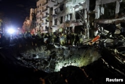 Israeli emergency responders inspect a crater at the site of a projectile impact after Iran launched missiles into Israel, in Tel Aviv.