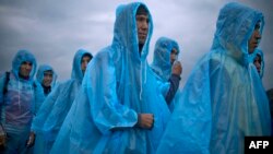 Migrants and refugees wearing raincoats queue at a camp to register after crossing the Greek-Macedonian border near Gevgelija, Macedonia.