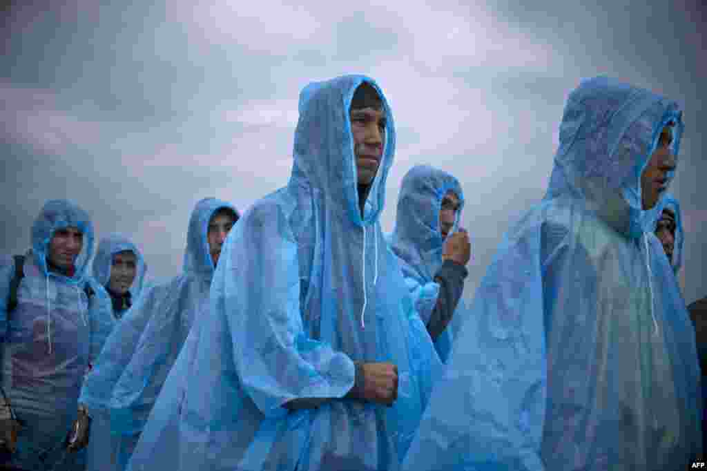 Migrants and refugees wearing raincoats queue at a camp to register after crossing the Greek-Macedonian border near Gevgelija, Macedonia. (AFP/Nikolay Doychinov)