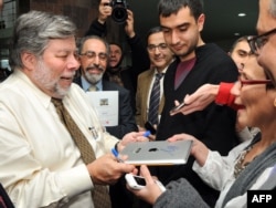 Steve Wozniak (left) autographs an Apple iPad during a meeting with students in Yerevan.