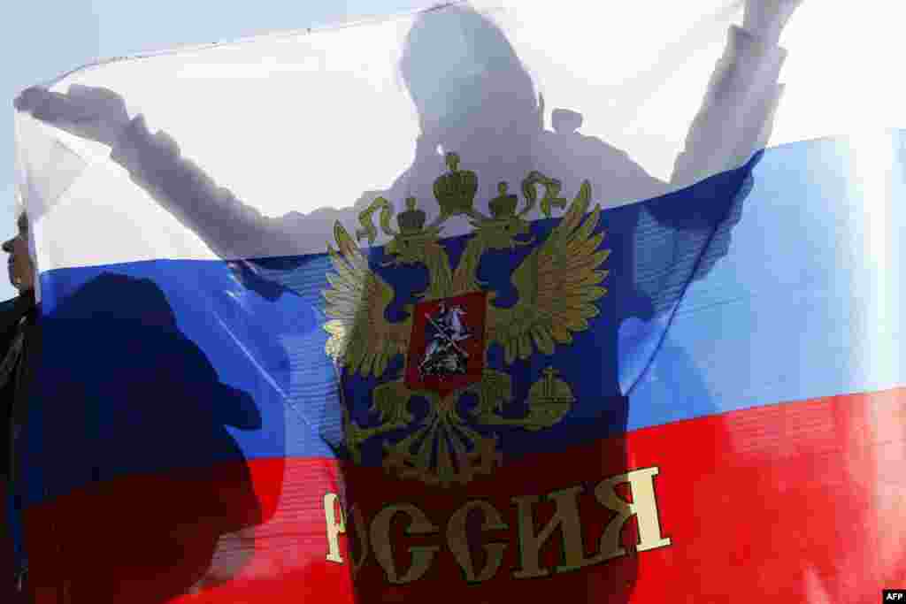 A woman holds a Russian national flag during a rally to support the self-rule "referendums" for the Ukrainian provinces of Donetsk and Luhansk in central Simferopol, Crimea, on May 11. (AFP/Max Vetrov)