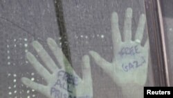 "Эркиндик флотилиясында" кармалган палестинчилердин бири Бииршеба түрмөсүнөн бошотулуп, автобуста баратканда колундагы жазуусун көрсөтүүдө.2-июнь 2010