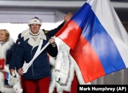 Aleksandr Zubkov of Russia carries the national flag as he leads the team during the opening ceremony of the 2014 Winter Olympics in Sochi, Russia, in February 2014. Zubkov was later banned in 2019 for two years on doping charges.