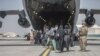 Afgán családoknak segít felszállni egy amerikai tengerészgyalog az amerikai légierő Boeing C-17 Globemaster gépére az evakuálás során a Hamid Karzai nemzetközi repülőtéren, Kabulban 2021. augusztus 23-án