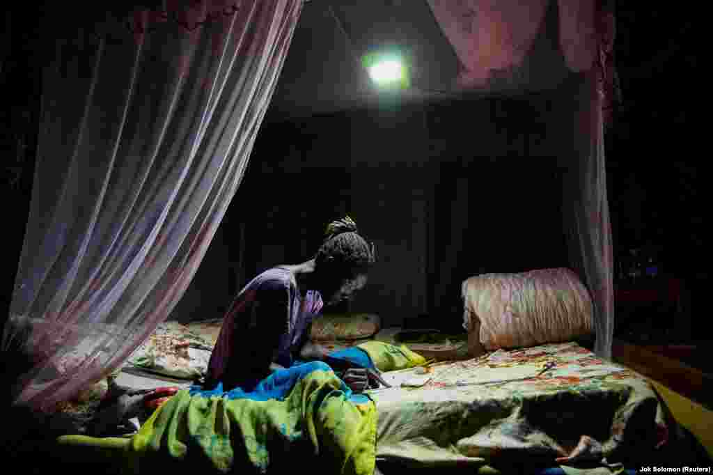 A South Sudanese girl uses a solar light to study amid electricity rationing in the African nation reportedly triggered by the US-Israeli conflict with Iran.