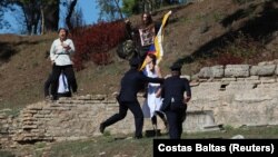 A protester holds a Tibetan flag as security officers intervene during the Olympic flame lighting ceremony for the Beijing 2022 Winter Olympics, in Athens on October 18. 