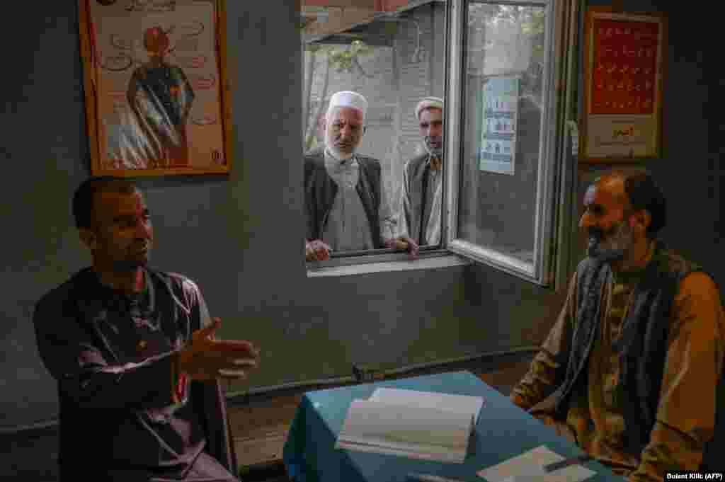 A new patient tries to convince an officer to let him leave as his family members watch through a window at the Avicenna Medical Hospital for Drug Treatment in Kabul on October 16.