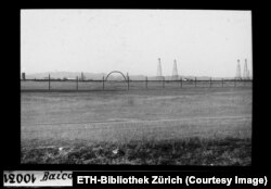 Derricks and an aboveground pipeline with arches for vehicles to pass under in Baicoi