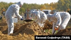 Cemetery workers wearing protective gear bury people who died of COVID-19 in Omsk.