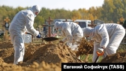 Рабочие одного из кладбищ в Омске в защитной одежде хоронят жертв эпидемии COVID-19 (архивный снимок)