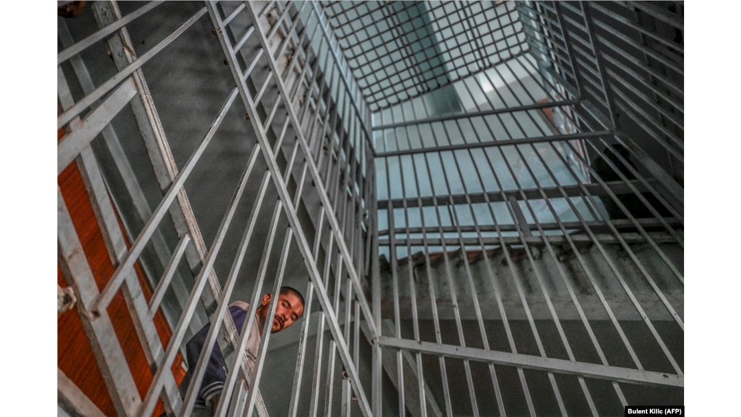 A drug addict looks through bars at an addiction-treatment center in Kabul.