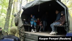 Iraqi migrants sit in a military truck after they were caught by border guards and police officers after crossing the Belarusian-Polish border in Hajnowka on October 14.