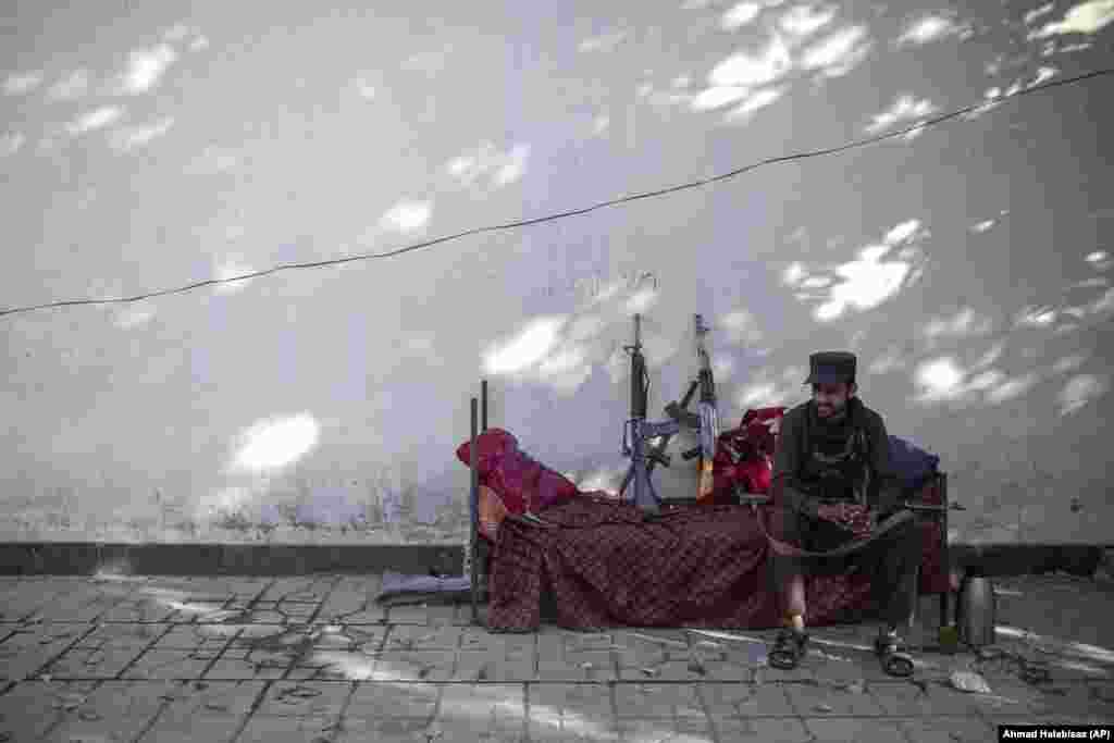 A Taliban fighter sits outside the government passport office in Kabul.&nbsp;