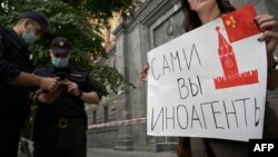 რუსეთი, უშიშროების ფედერალური სამსახურის წინ მდგარ ჟურნალისტს უკავია პლაკატი წარწერით : "თავად ხართ "უცხოური აგენტები"