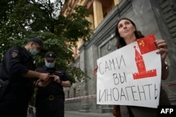A journalist holds a placard which reads "Foreign agents yourself" near the headquarters of Federal Security Service in Moscow in August 2021, soon after Russia added Dozhd to a growing list of "foreign agent" media outlets.