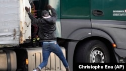 Egy migráns ugrik fel egy Franciaországból Nagy-Britanniába tartó kamionra Calais-ban 2021. október 14-én. A gyakorlat veszélyes, sőt néha halálos. Kamionokon elrejtőzve próbálnak átjutni a rendőrök által keményen őrzött Csalagúton a papírok nélküli afrikai és közel-keleti menekültek