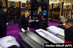 Participants in the event, being held in Moscow's Expocentre, arrange a display of coffins.