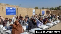 Afganistanci sjede pored vreća sa žitaricama koje im je podijelio Svjetski program za hranu, Kandahar, 19. oktobar 2021.