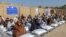 Afghans sit beside sacks of food grains distributed as aid by the World Food Program in Kandahar on October 19.