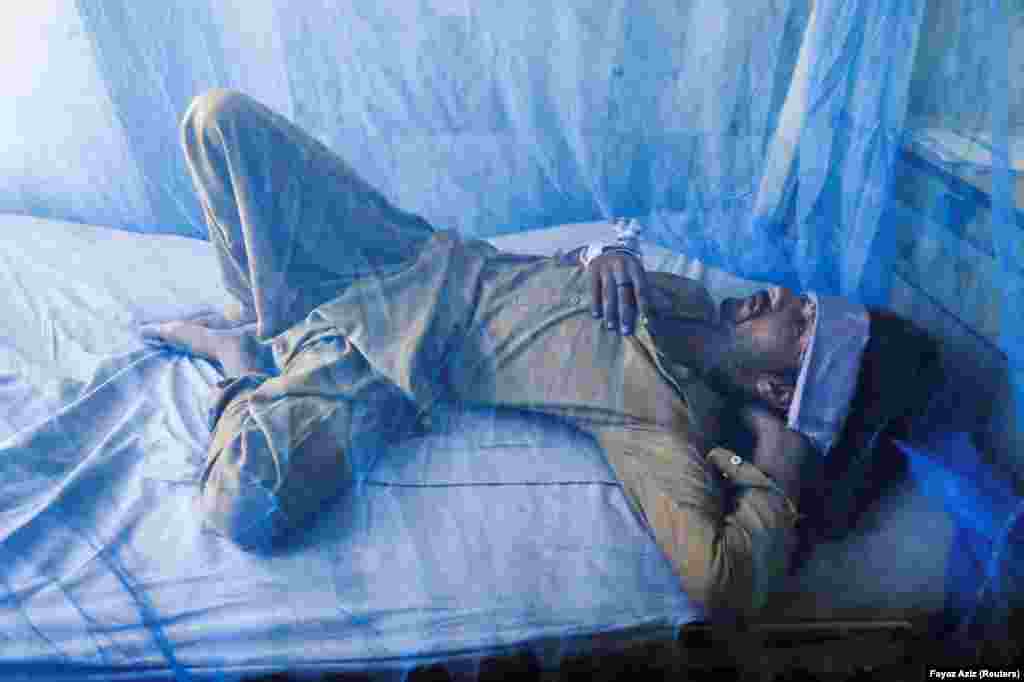 Szúnyogháló alatt pihen egy dengue-lázban szenvedő beteg egy pakisztáni kórházban