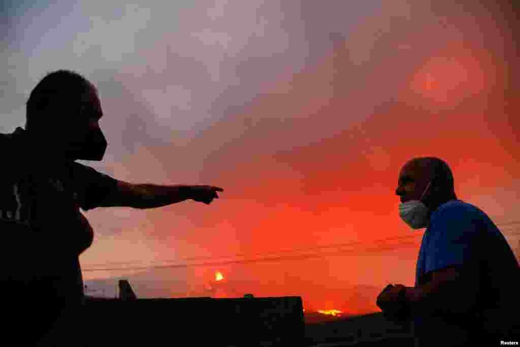 Двоє чоловіків, яких місяць тому евакуювали зі своїх будинків, розмовляють, дивлячись на вулкан Кумбре-В&rsquo;єха на Канарському острові Ла-Пальма, Іспанія, 22 жовтня 2021 року. Погляд з&nbsp;Таджуйе