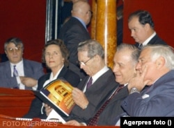 Regele Mihai, Regina Ana, alături de președintele Ion Iliescu, fost oficial comunist, aflat la cel de-al doilea mandat în fruntea României și oficiali de la Președinție. În 2001, regimul Iliescu/Năstase a continuat demersurile inițiate de Convenție Democratică de aderare la NATO și Uniunea Europeană. Avea nevoie de un ambasador credibil. Regele Mihai a fost acest ambasador. Care au fost condițiile, le rămâne istoricilor să dezlege enigma. Aici, pe 19 decembrie 2001, la Opera din Timișoara. Catedrala din apropiere e ctitoria Regelui Mihai.