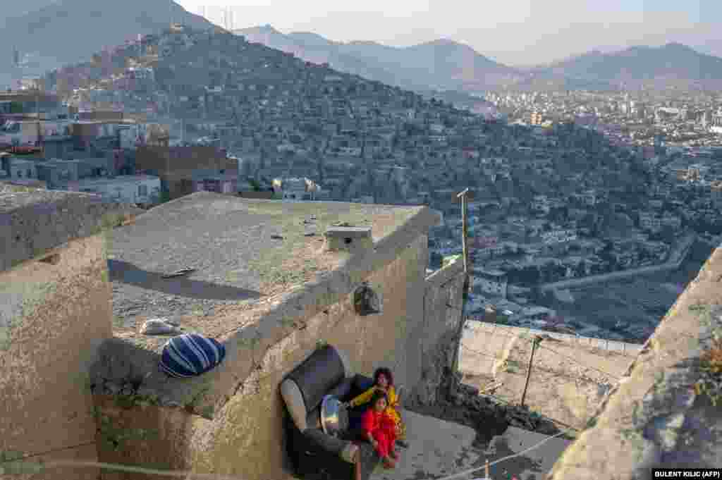 Афганские дети сидят на диване в своем доме с видом на Кабул