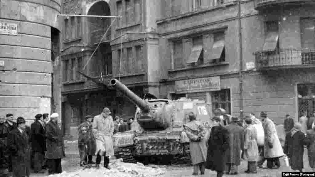 Budapest VIII. kerület, a Déri Miksa és a mai Fecske, akkori Lévai Oszkár utca sarka. Az archív fotón egy ISZU 152-es rohamlöveget mustrálnak az emberek.