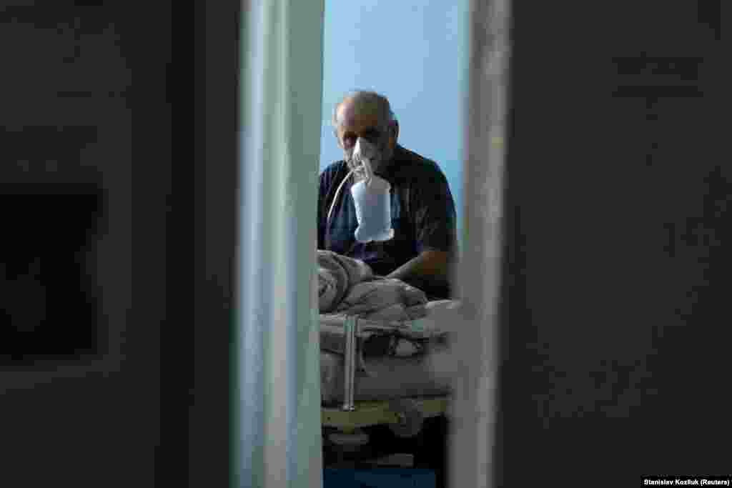 Un pacient care suferă de Covid-19 respiră cu ajutorul unei măști cu oxigen, la unitatea de terapie intensivă a Spitalului Clinic Orășenesc numărul 3 din Kiev, Ucraina.