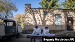 Հիվանդանոցի դիարանի բժիշկները կորոնավիրուսից մահացած հիվանդի դին տեղավորում են դագաղի մեջ, Ռովնո, Ուկրաինա, 22 հոկտեմբերի, 2021թ.