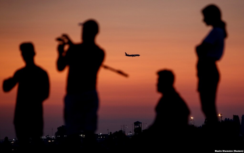 An airplane flies over people on a beach in Russia&#39;s Black Sea resort of Sochi.