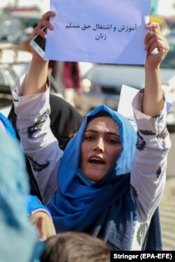 An Afghan woman holds a sign saying, "Education and employment are the inalienable rights of Muslim women."