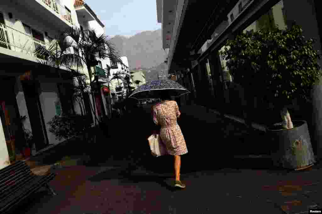 Жінка на вулиці в Льянос-де-Арідан ховається від вулканічного попелу під парасолькою. Канарський острів Ла-Пальма, Іспанія, 18 жовтня 2021 року